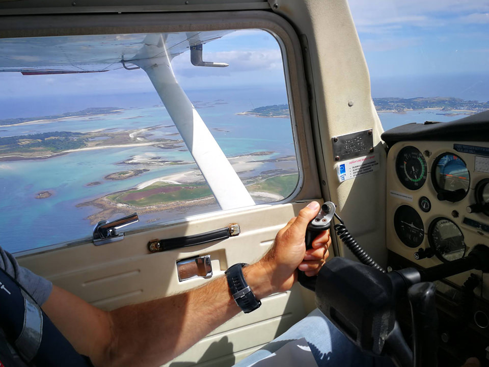 Student pilot at the controls of the Cessna 152 flying over the Isles of Scilly, Cornwall.